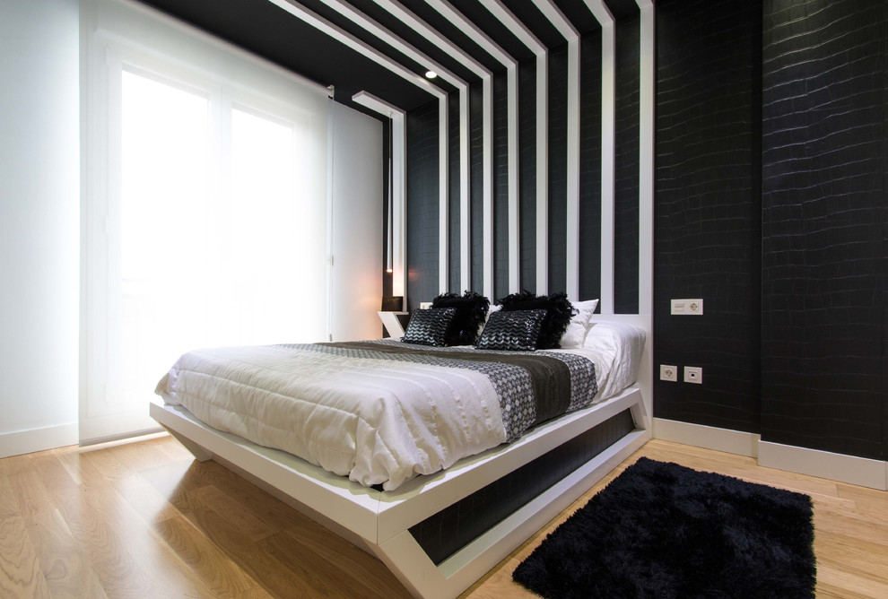 Large contemporary master bedroom in Bilbao with light hardwood floors and black walls.