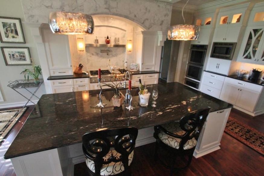 Mid-sized transitional u-shaped dark wood floor enclosed kitchen photo with a drop-in sink, flat-panel cabinets, white cabinets, granite countertops, white backsplash, stainless steel appliances and an island