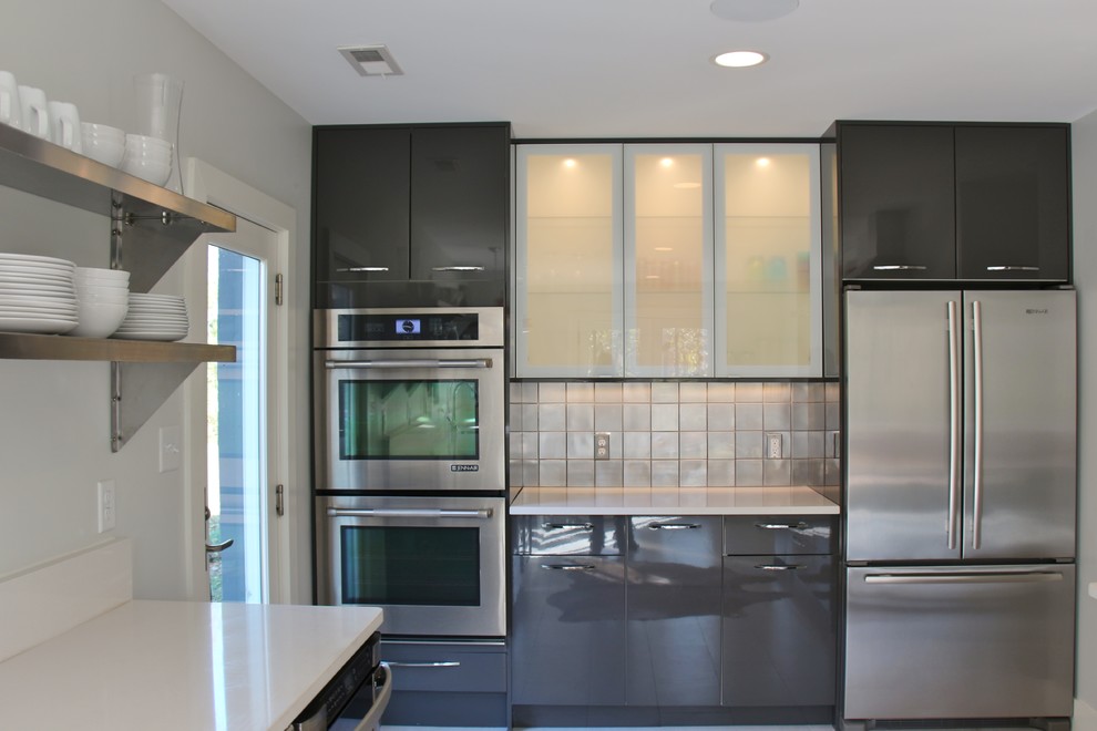 Photo of a mid-sized modern galley eat-in kitchen in Orlando with a double-bowl sink, flat-panel cabinets, grey cabinets, granite benchtops, metallic splashback, stainless steel appliances, porcelain floors and no island.