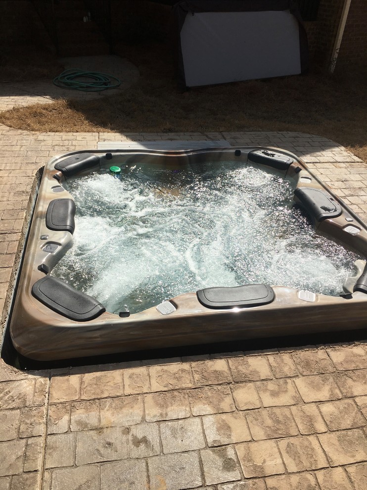 Inspiration for a mid-sized transitional backyard stamped concrete and rectangular hot tub remodel