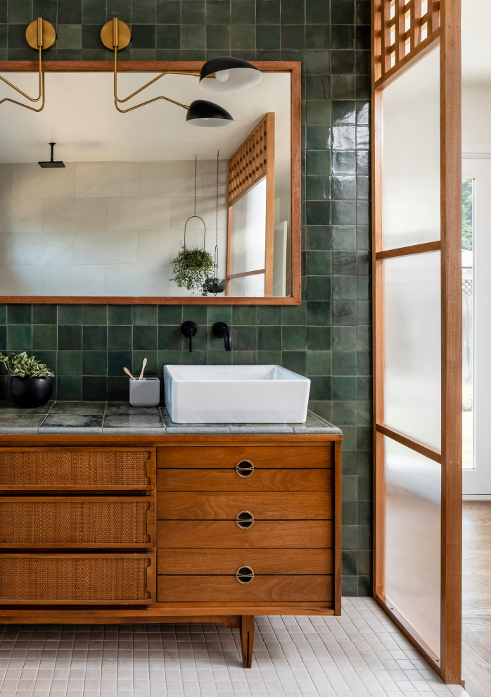 This is an example of a mid-sized master bathroom in Sacramento with brown cabinets, an open shower, green tile, subway tile, green walls, ceramic floors, a vessel sink, tile benchtops, white floor, an open shower, green benchtops, a shower seat, a double vanity and a built-in vanity.