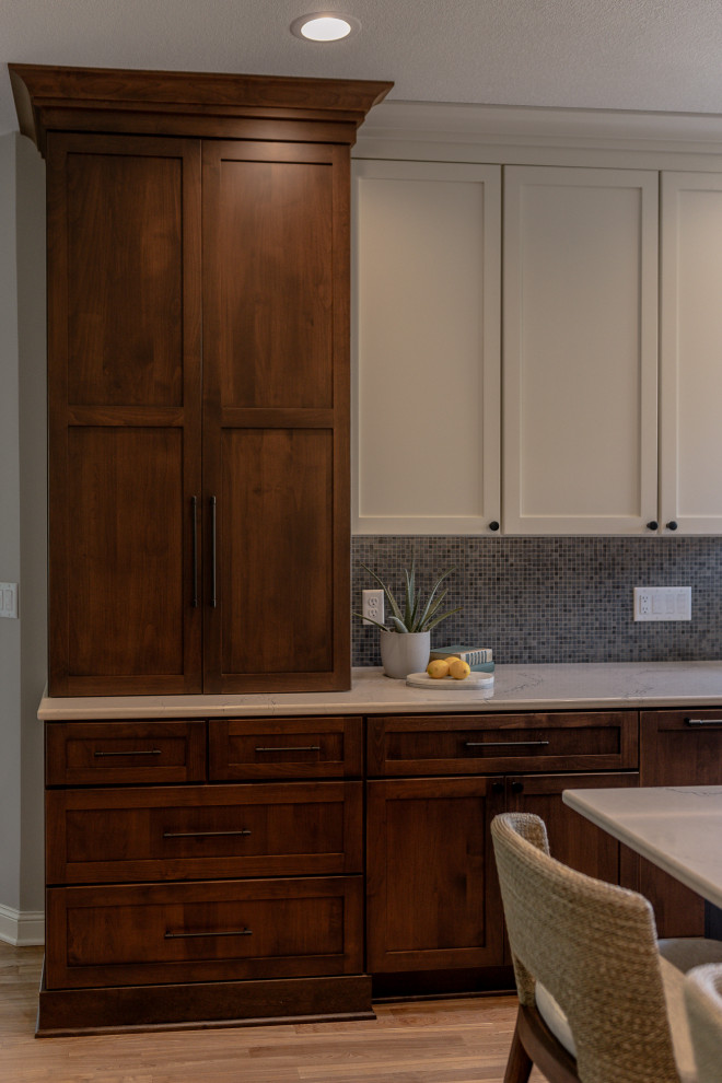 Example of a mid-sized transitional l-shaped medium tone wood floor and brown floor eat-in kitchen design with an undermount sink, recessed-panel cabinets, dark wood cabinets, quartz countertops, blue backsplash, mosaic tile backsplash, stainless steel appliances, an island and white countertops