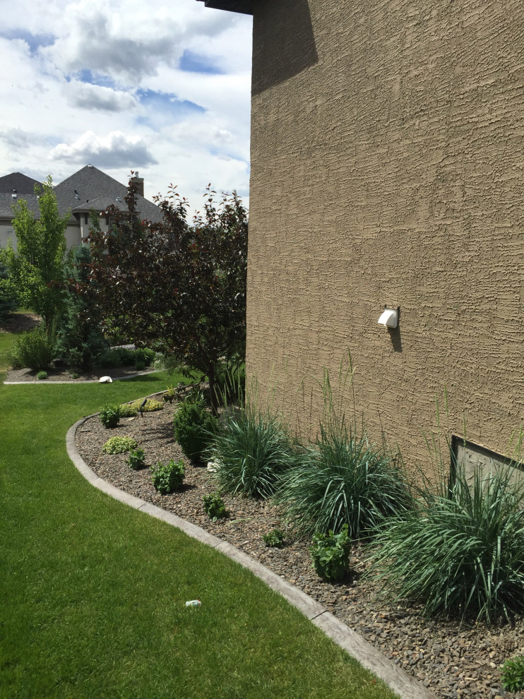 This is an example of a large side yard garden in Calgary with with lawn edging and gravel.