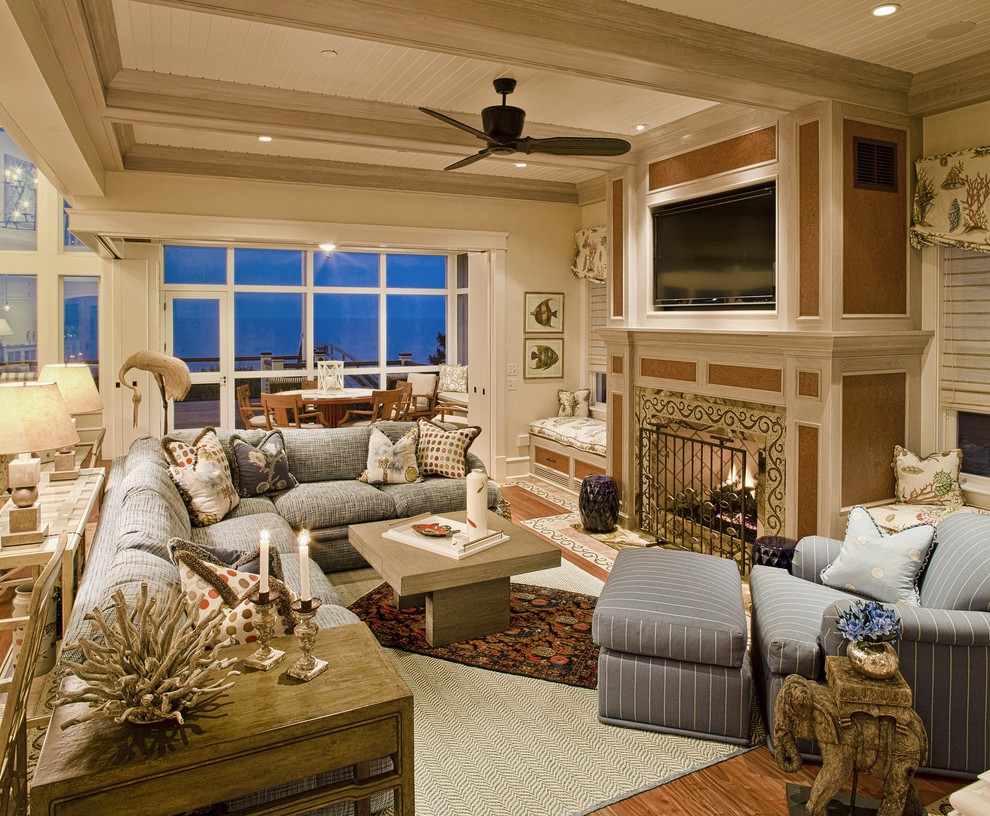 Inspiration for a large beach style living room in Philadelphia with beige walls, medium hardwood floors, a standard fireplace, a stone fireplace surround and a concealed tv.