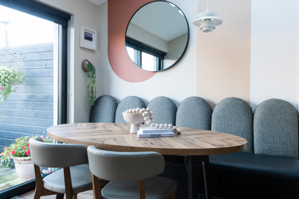 Inspiration pour une salle à manger ouverte sur la cuisine minimaliste de taille moyenne avec un mur multicolore, sol en stratifié, un sol marron et un plafond voûté.