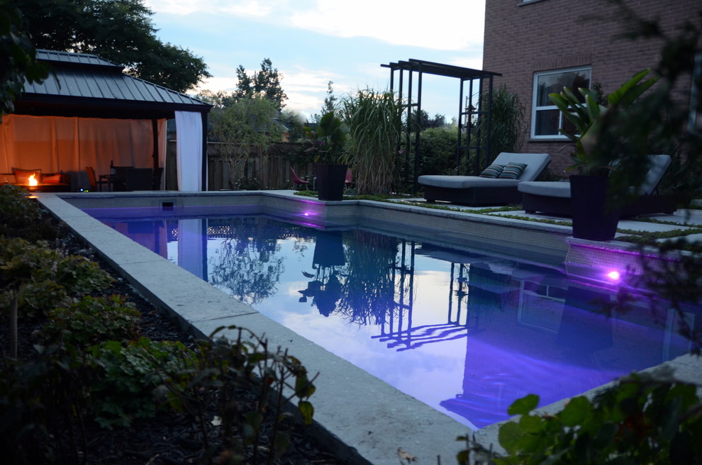 Photo of a small contemporary backyard rectangular pool in Toronto with concrete slab.