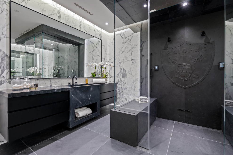 Contemporary bathroom in Las Vegas with flat-panel cabinets, black cabinets, a curbless shower, white tile, an integrated sink, grey floor, a hinged shower door, black benchtops, a shower seat, a single vanity and a floating vanity.