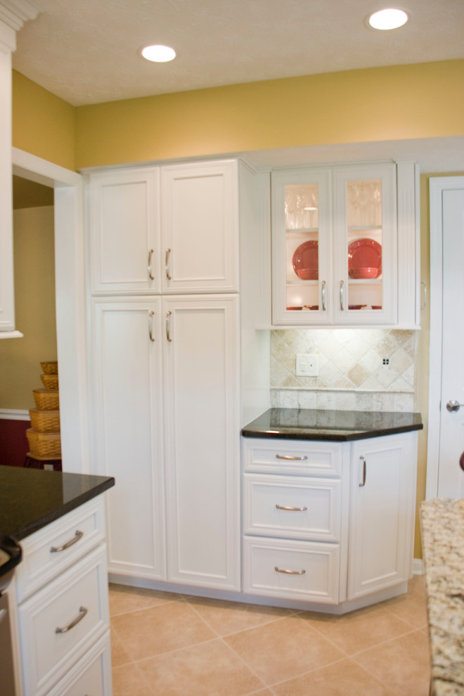 Inspiration for a mid-sized transitional l-shaped vinyl floor eat-in kitchen remodel with an undermount sink, recessed-panel cabinets, white cabinets, beige backsplash, stone tile backsplash, stainless steel appliances and an island
