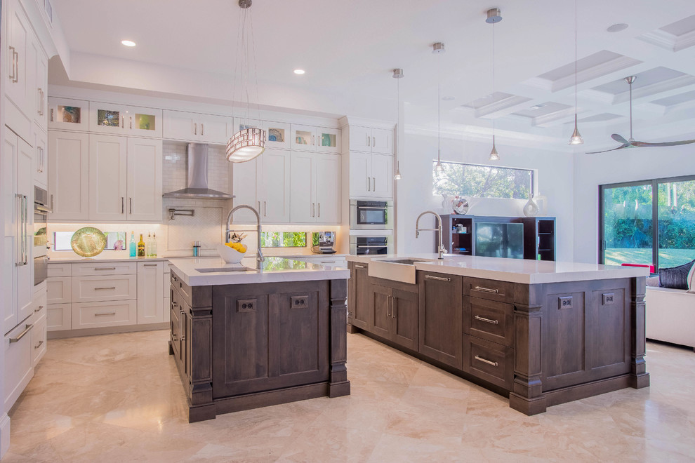 Huge transitional l-shaped porcelain tile and beige floor open concept kitchen photo with a farmhouse sink, shaker cabinets, white cabinets, quartz countertops, white backsplash, porcelain backsplash, stainless steel appliances and two islands