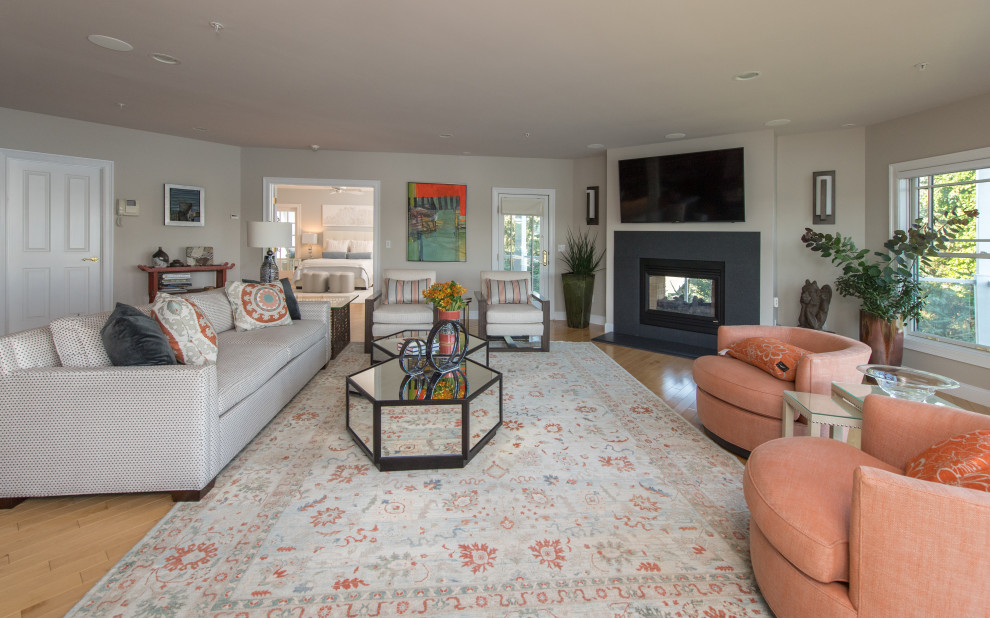 Large transitional enclosed living room in Boston with beige walls, light hardwood floors, a corner fireplace, a concrete fireplace surround, a wall-mounted tv and orange floor.