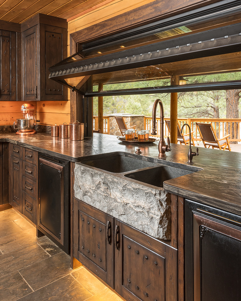 Small country l-shaped eat-in kitchen in Phoenix with a farmhouse sink, distressed cabinets, granite benchtops, brown splashback, black appliances, slate floors and grey floor.