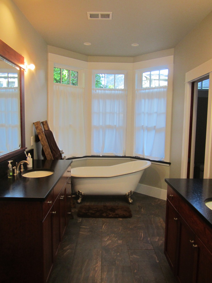 Design ideas for a mid-sized arts and crafts master bathroom in Denver with shaker cabinets, dark wood cabinets, a claw-foot tub, a two-piece toilet, beige walls, dark hardwood floors, an undermount sink and soapstone benchtops.