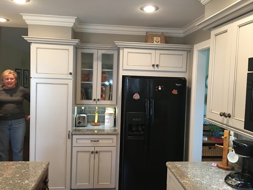 Elegant dark wood floor eat-in kitchen photo with a double-bowl sink, raised-panel cabinets, white cabinets, quartz countertops, gray backsplash, ceramic backsplash, black appliances and an island