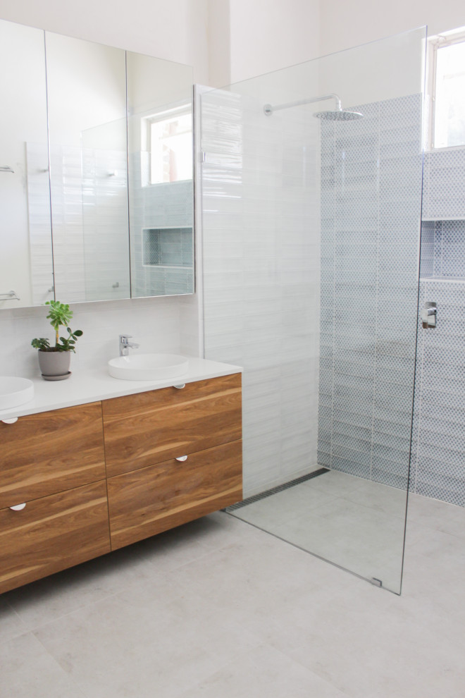 Photo of a large modern kids bathroom in Perth with flat-panel cabinets, dark wood cabinets, an open shower, a two-piece toilet, blue tile, subway tile, blue walls, porcelain floors, a vessel sink, engineered quartz benchtops, grey floor, an open shower and white benchtops.