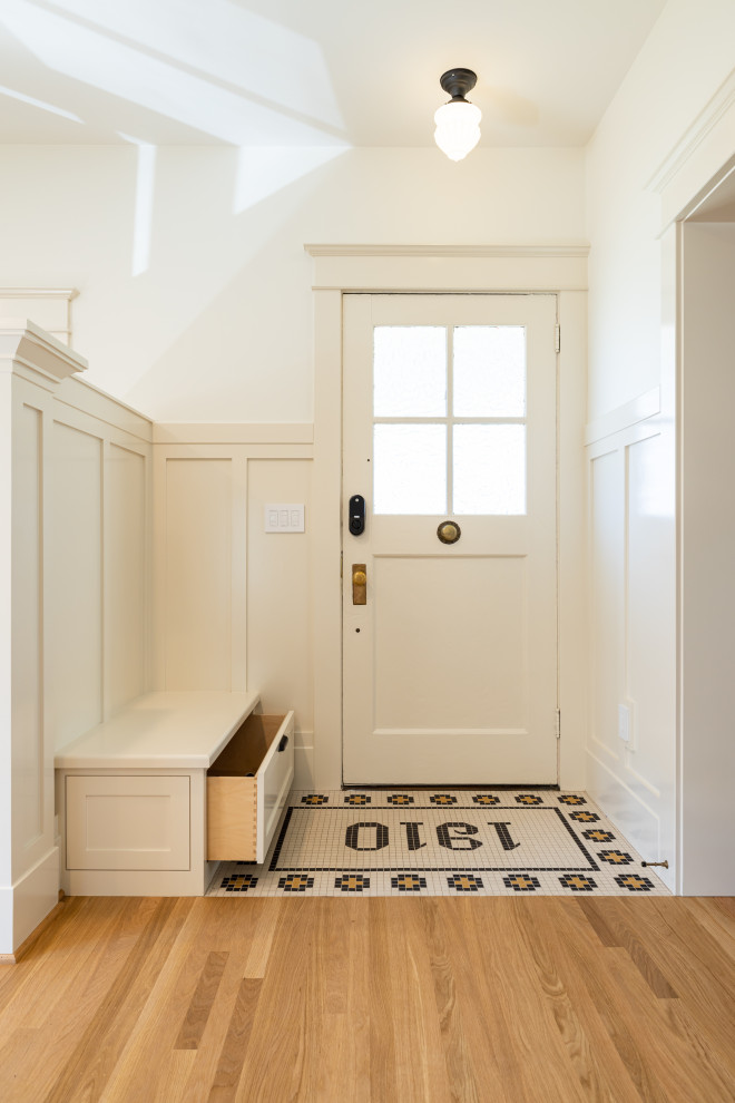Cette photo montre une entrée craftsman avec un mur blanc, un sol en bois brun, une porte simple, une porte blanche, poutres apparentes et boiseries.
