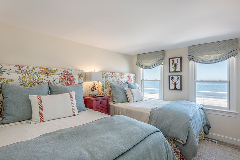 This is an example of a large beach style guest bedroom in Boston with beige walls, light hardwood floors, no fireplace and beige floor.