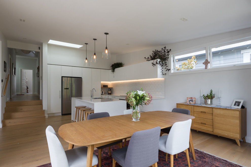 This is an example of a mid-sized contemporary kitchen/dining combo in Auckland with white walls, medium hardwood floors and brown floor.