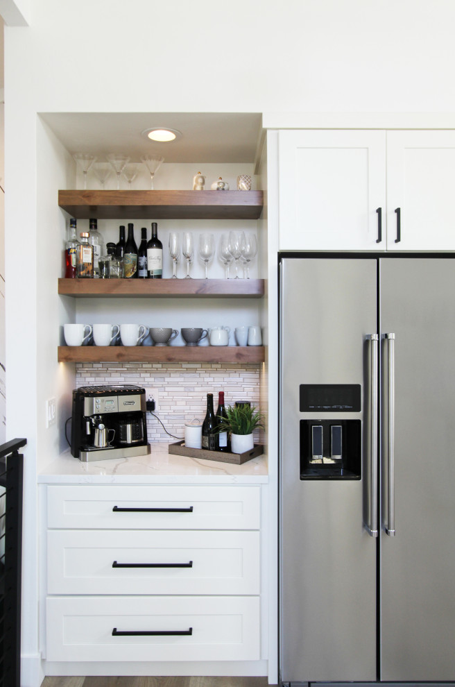Mid-sized transitional l-shaped vinyl floor, brown floor and vaulted ceiling eat-in kitchen photo with an undermount sink, shaker cabinets, white cabinets, quartz countertops, multicolored backsplash, mosaic tile backsplash, stainless steel appliances, an island and white countertops