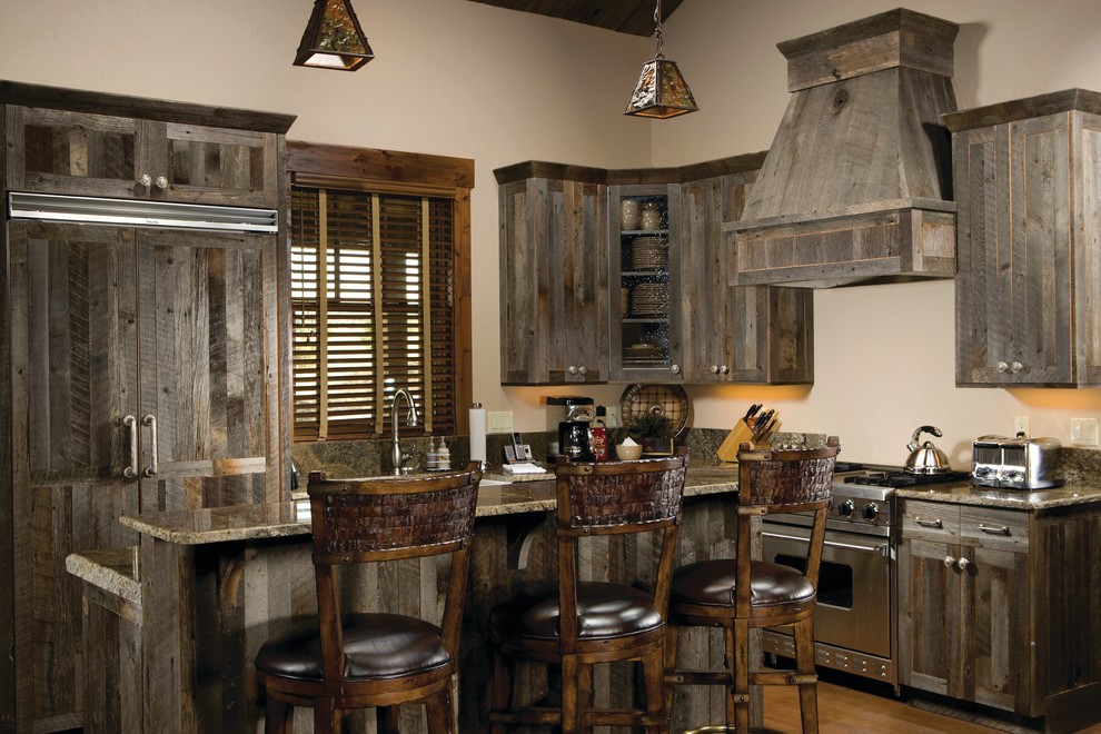Mid-sized country l-shaped eat-in kitchen in Other with panelled appliances, with island, a farmhouse sink, shaker cabinets, distressed cabinets, granite benchtops, medium hardwood floors and brown floor.