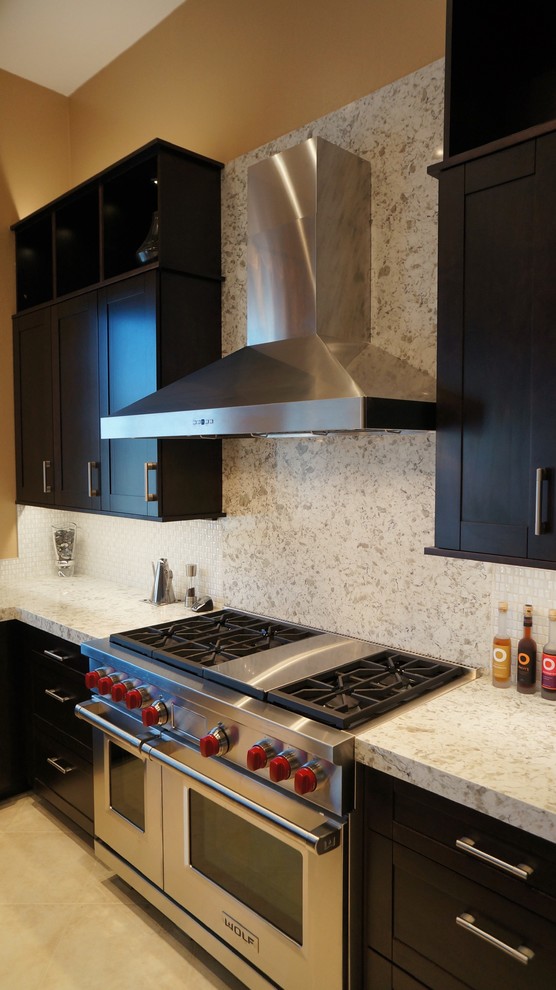 Example of a transitional l-shaped porcelain tile and beige floor kitchen design in Phoenix with an undermount sink, recessed-panel cabinets, dark wood cabinets, quartz countertops, white backsplash, ceramic backsplash, stainless steel appliances and an island
