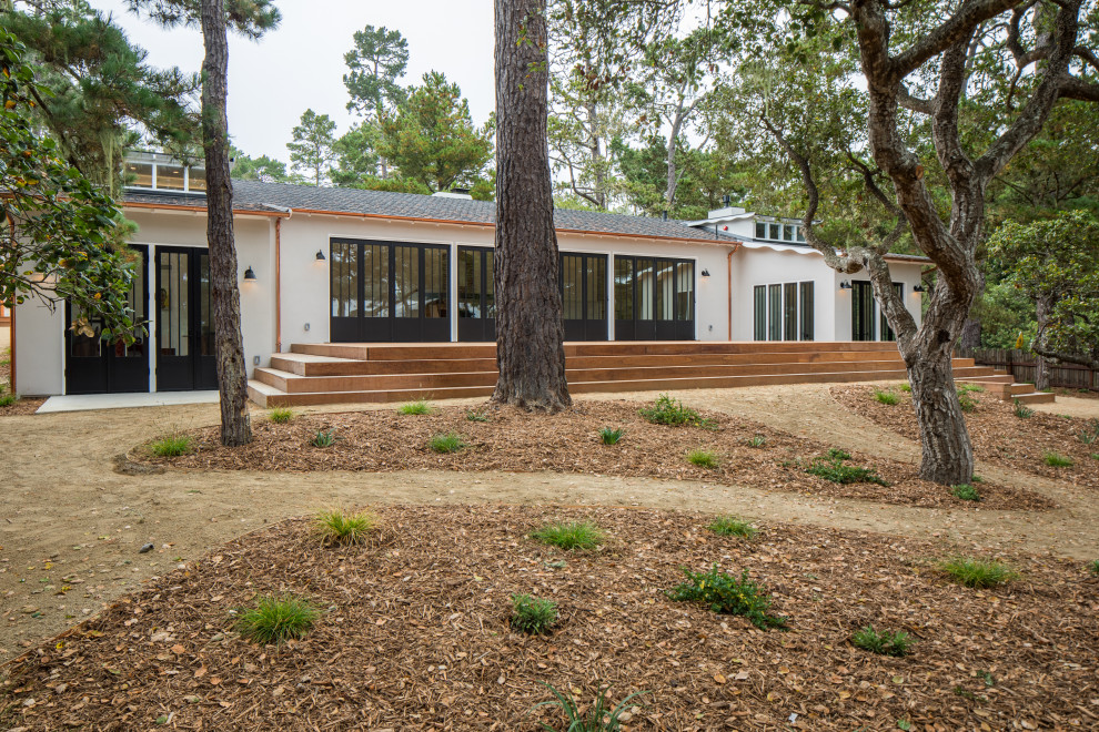 Large transitional beige split-level stucco house exterior photo with a hip roof and a shingle roof