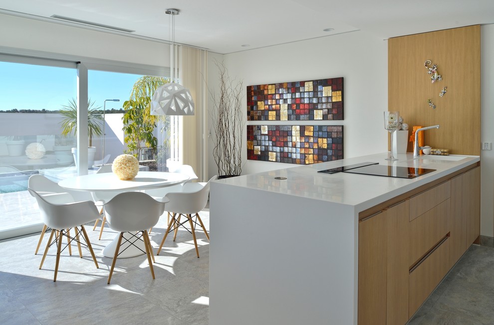This is an example of a mid-sized mediterranean single-wall open plan kitchen in Alicante-Costa Blanca with flat-panel cabinets, light wood cabinets, quartz benchtops and a peninsula.