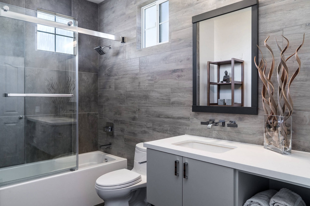 Design ideas for a large modern master bathroom in San Diego with shaker cabinets, grey cabinets, an alcove tub, a shower/bathtub combo, a one-piece toilet, brown tile, wood-look tile, brown walls, an undermount sink, a sliding shower screen, white benchtops, a single vanity and a built-in vanity.