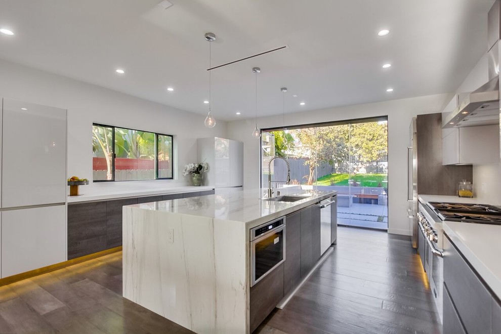 Large minimalist single-wall medium tone wood floor and brown floor enclosed kitchen photo in Hawaii with an undermount sink, flat-panel cabinets, gray cabinets, solid surface countertops, stainless steel appliances, an island and white countertops