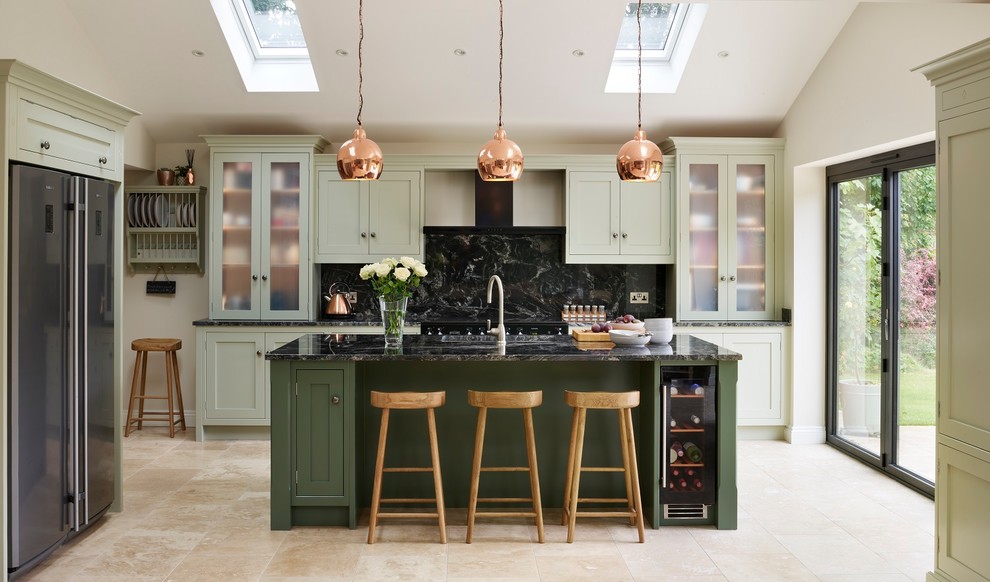 This is an example of a transitional galley kitchen in Essex with an undermount sink, shaker cabinets, green cabinets, black splashback, stone slab splashback, stainless steel appliances, with island, beige floor and black benchtop.