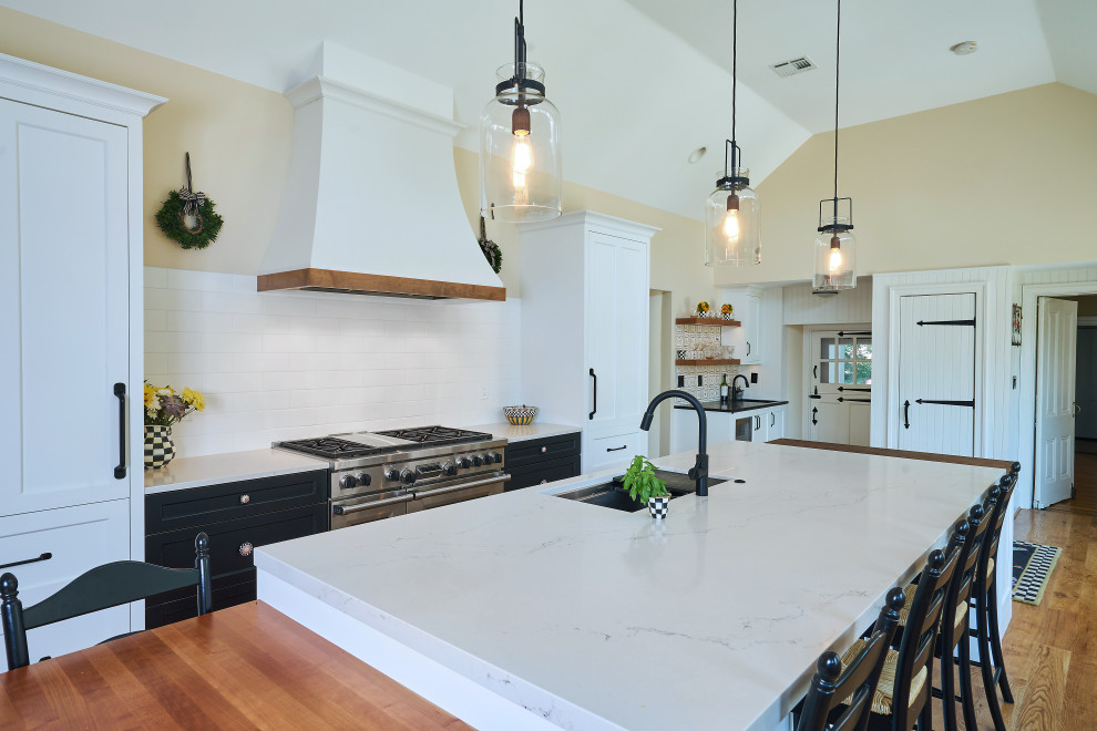 Large country medium tone wood floor and brown floor kitchen photo in Philadelphia with an undermount sink, shaker cabinets, white cabinets, quartz countertops, white backsplash, porcelain backsplash, paneled appliances, an island and white countertops