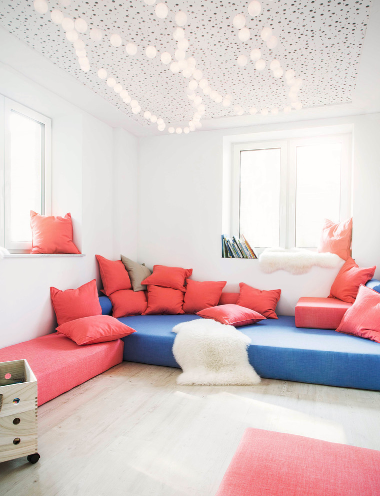 Photo of a mid-sized scandinavian gender-neutral kids' playroom for kids 4-10 years old in Hamburg with white walls and light hardwood floors.