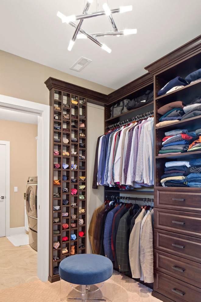 This is an example of a mid-sized transitional men's walk-in wardrobe in Cincinnati with raised-panel cabinets, dark wood cabinets, carpet and beige floor.