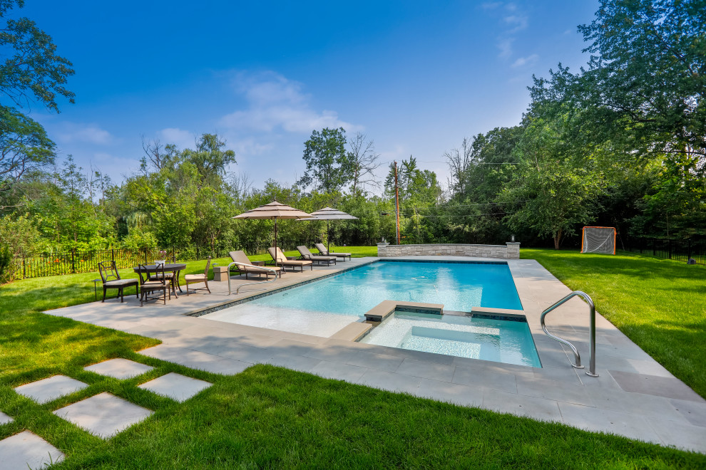 Modelo de piscina alargada clásica de tamaño medio rectangular en patio trasero con privacidad y adoquines de piedra natural