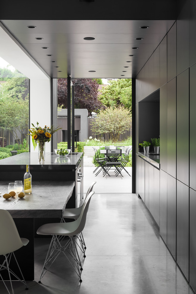 Photo of an expansive contemporary single-wall open plan kitchen in London with a drop-in sink, flat-panel cabinets, grey cabinets, solid surface benchtops, panelled appliances, concrete floors, with island and grey floor.