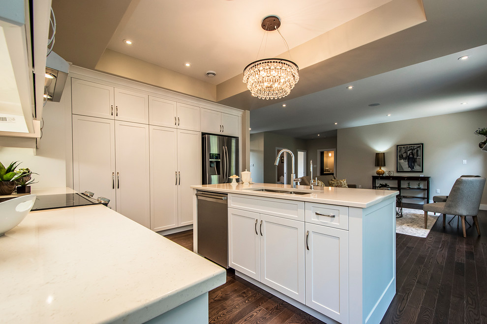 Example of a large transitional l-shaped dark wood floor open concept kitchen design with a double-bowl sink, shaker cabinets, white cabinets, quartzite countertops, beige backsplash, porcelain backsplash, stainless steel appliances and an island
