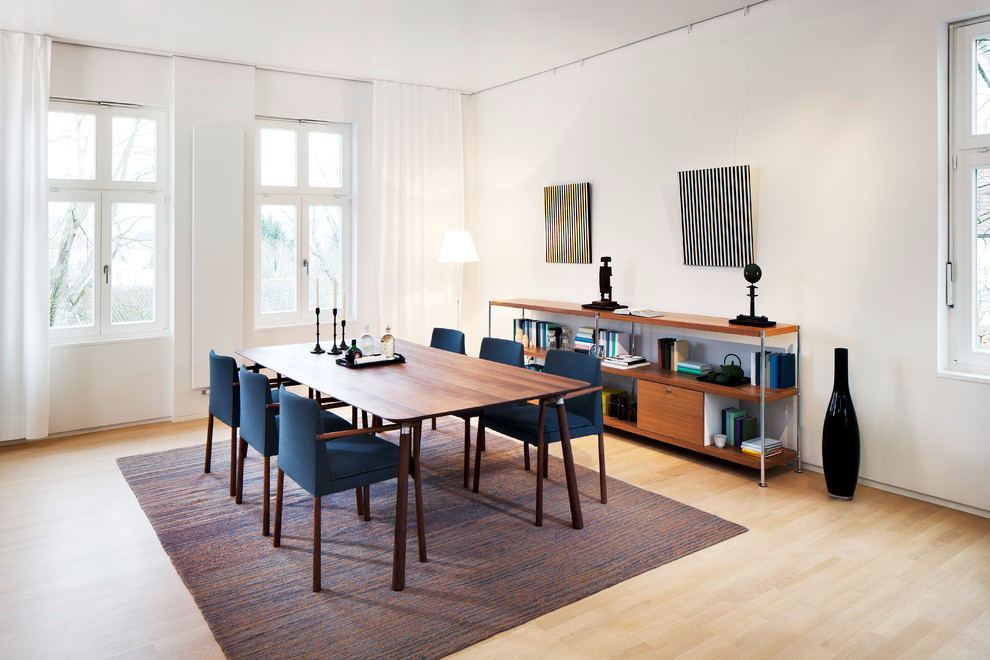 Photo of a mid-sized midcentury dining room in Stuttgart with white walls and light hardwood floors.
