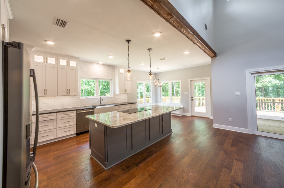 Inspiration for a mid-sized timeless galley medium tone wood floor and brown floor eat-in kitchen remodel with a farmhouse sink, recessed-panel cabinets, white cabinets, quartzite countertops, white backsplash, glass tile backsplash, stainless steel appliances, an island and multicolored countertops