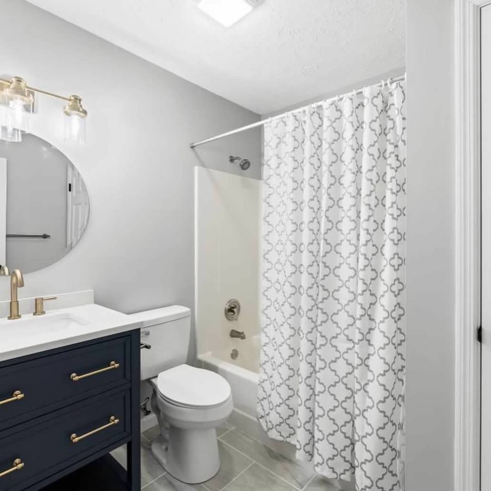 Réalisation d'une salle de bain minimaliste de taille moyenne avec des portes de placard bleues, une baignoire en alcôve, un combiné douche/baignoire, WC séparés, un mur gris, un sol en carrelage de porcelaine, un lavabo encastré, un plan de toilette en granite, un sol gris, un plan de toilette blanc et meuble simple vasque.