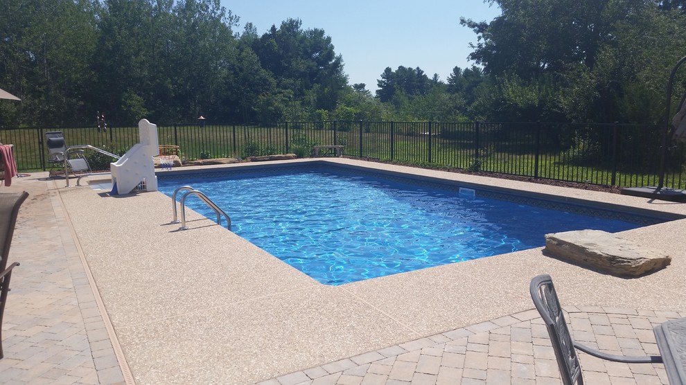 Design ideas for a mid-sized traditional backyard rectangular lap pool in Manchester with a hot tub and brick pavers.