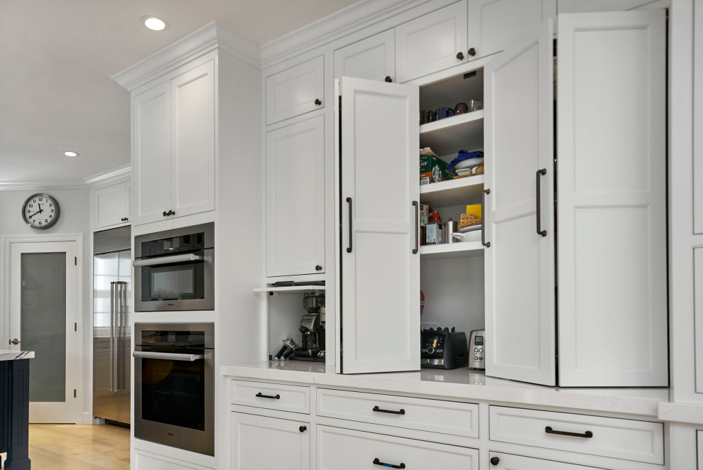 Inspiration for a large transitional l-shaped kitchen pantry in San Francisco with an undermount sink, beaded inset cabinets, white cabinets, quartz benchtops, white splashback, ceramic splashback, stainless steel appliances, light hardwood floors, with island, yellow floor and blue benchtop.