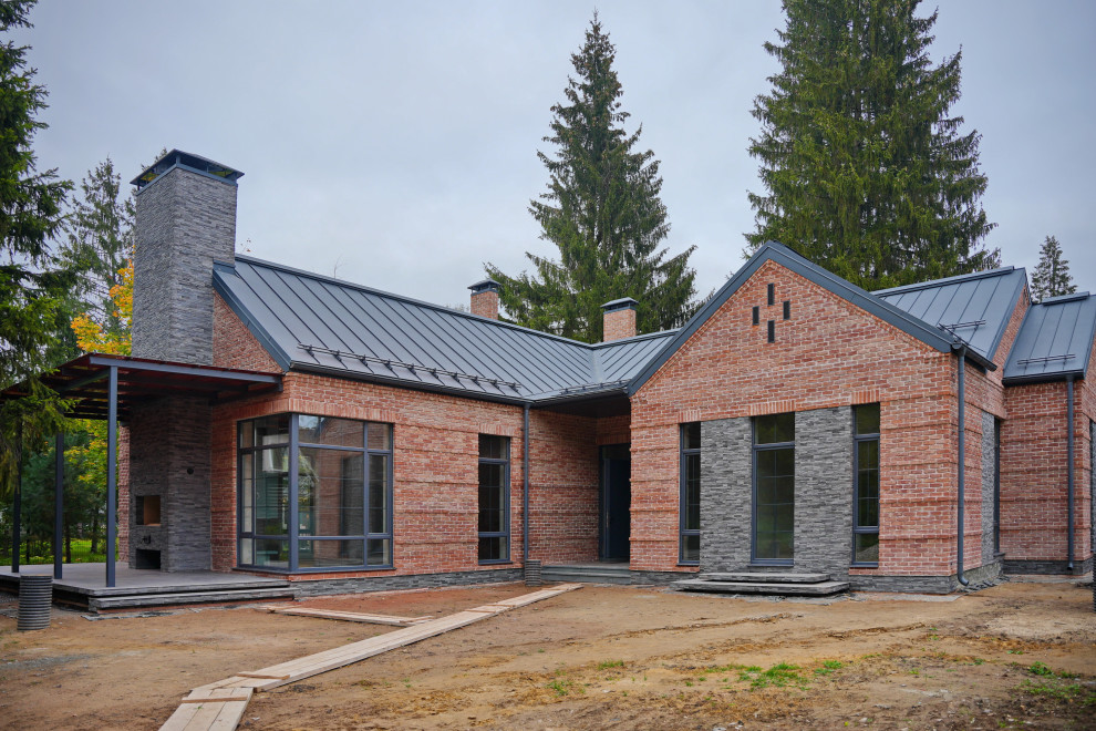 Aménagement d'une façade de maison rouge montagne en brique de taille moyenne et de plain-pied avec un toit à deux pans, un toit en métal et un toit gris.
