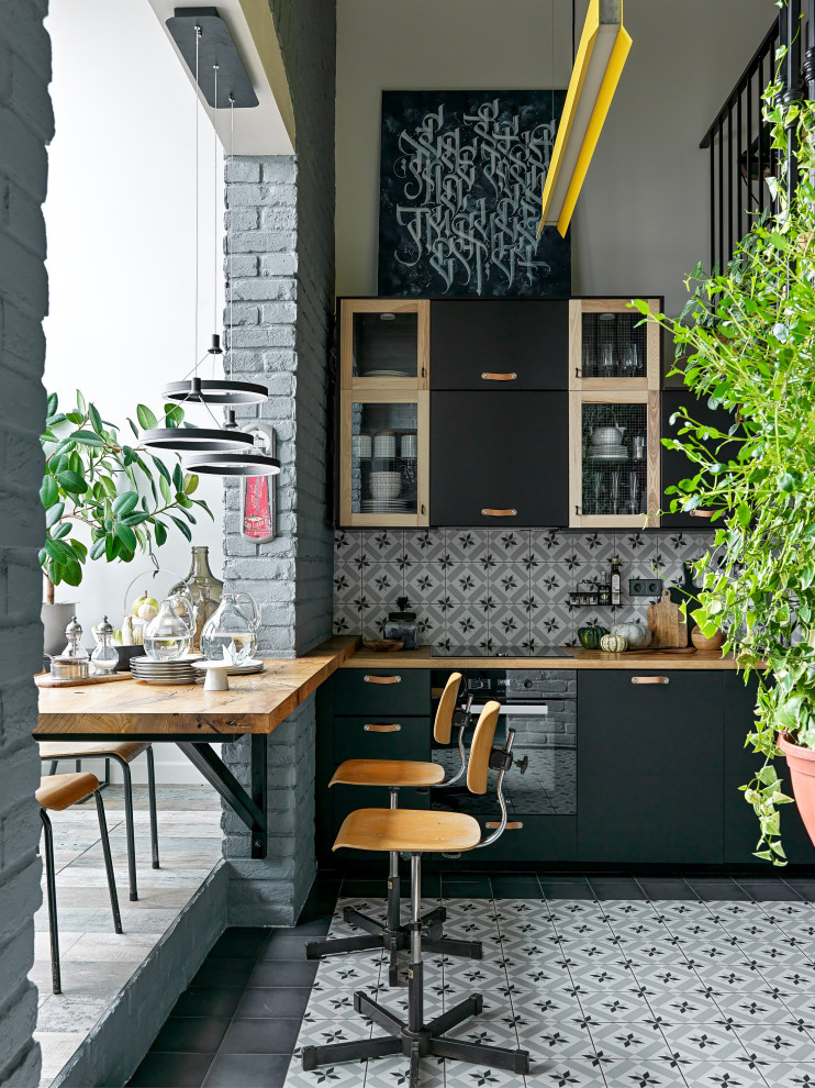 Inspiration for a mid-sized industrial l-shaped eat-in kitchen in Moscow with an undermount sink, flat-panel cabinets, black cabinets, wood benchtops, multi-coloured splashback, ceramic splashback, black appliances, ceramic floors, no island, blue floor and brown benchtop.