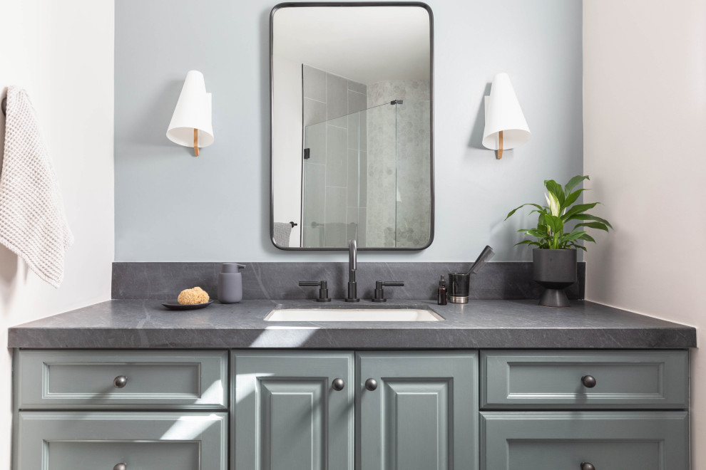 Inredning av ett mellanstort grå grått badrum med dusch, med släta luckor, grå skåp, grå väggar, ett undermonterad handfat och bänkskiva i täljsten