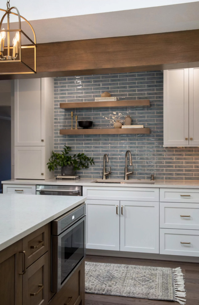 Example of a beach style l-shaped brown floor and exposed beam kitchen design with recessed-panel cabinets, white cabinets, quartzite countertops, blue backsplash, stainless steel appliances, an island and white countertops