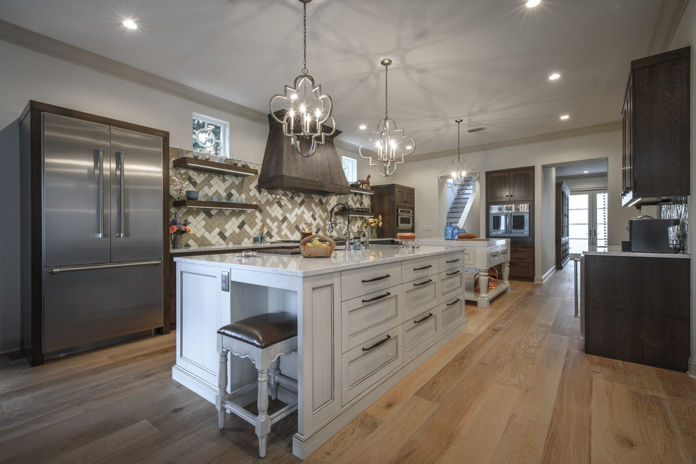 Inspiration for a large transitional galley light wood floor kitchen remodel in Jacksonville with a double-bowl sink, shaker cabinets, quartz countertops, brown backsplash, ceramic backsplash, stainless steel appliances, dark wood cabinets and two islands