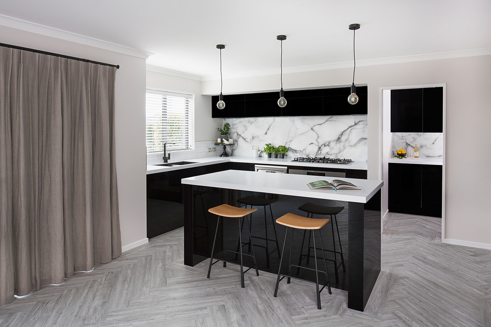Photo of a mid-sized modern l-shaped open plan kitchen in Christchurch with a double-bowl sink, flat-panel cabinets, black cabinets, white splashback, marble splashback, stainless steel appliances, vinyl floors, with island, grey floor and white benchtop.