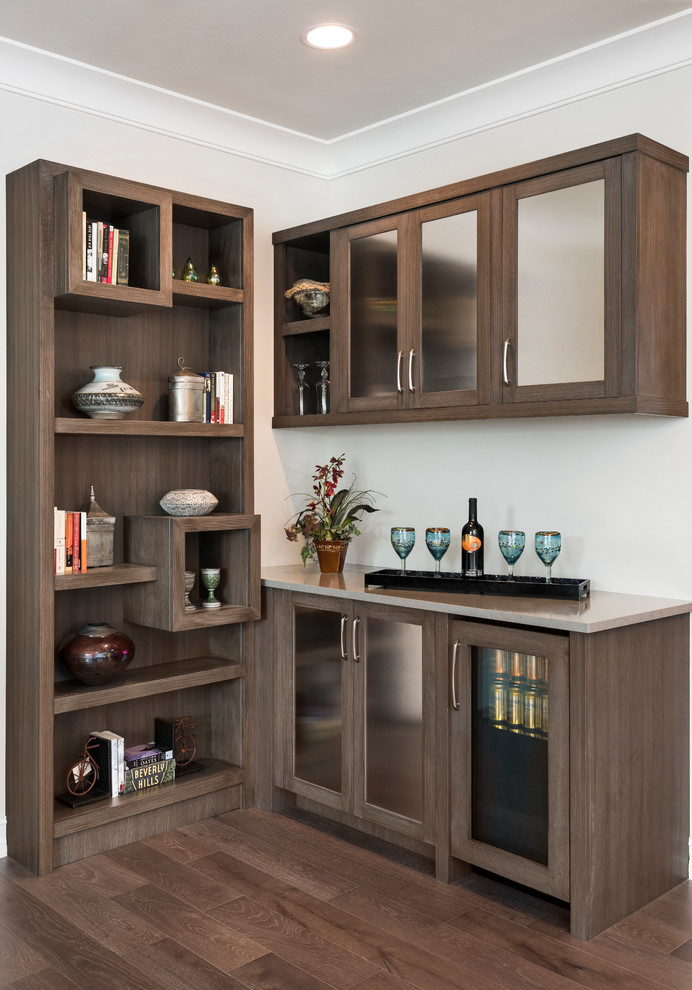 Design ideas for a small transitional l-shaped wet bar in Miami with no sink, dark wood cabinets, dark hardwood floors, brown floor, quartzite benchtops and glass-front cabinets.