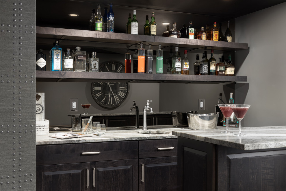 Small transitional galley wet bar in New York with a drop-in sink, shaker cabinets, dark wood cabinets, granite benchtops, yellow splashback, mirror splashback, vinyl floors, brown floor and multi-coloured benchtop.