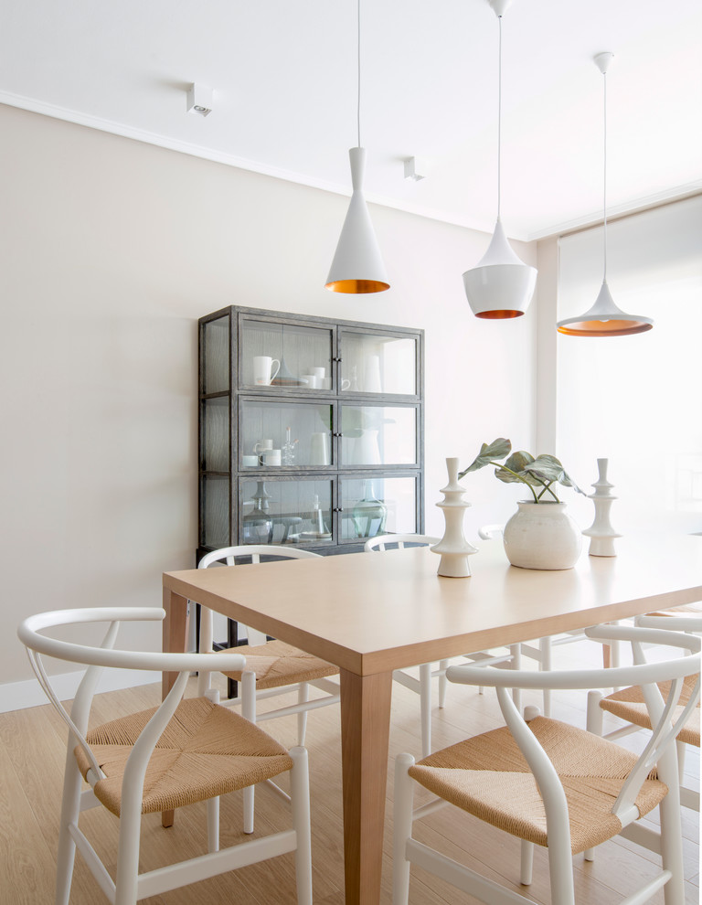 Mid-sized scandinavian open plan dining in Bilbao with beige walls, light hardwood floors and no fireplace.