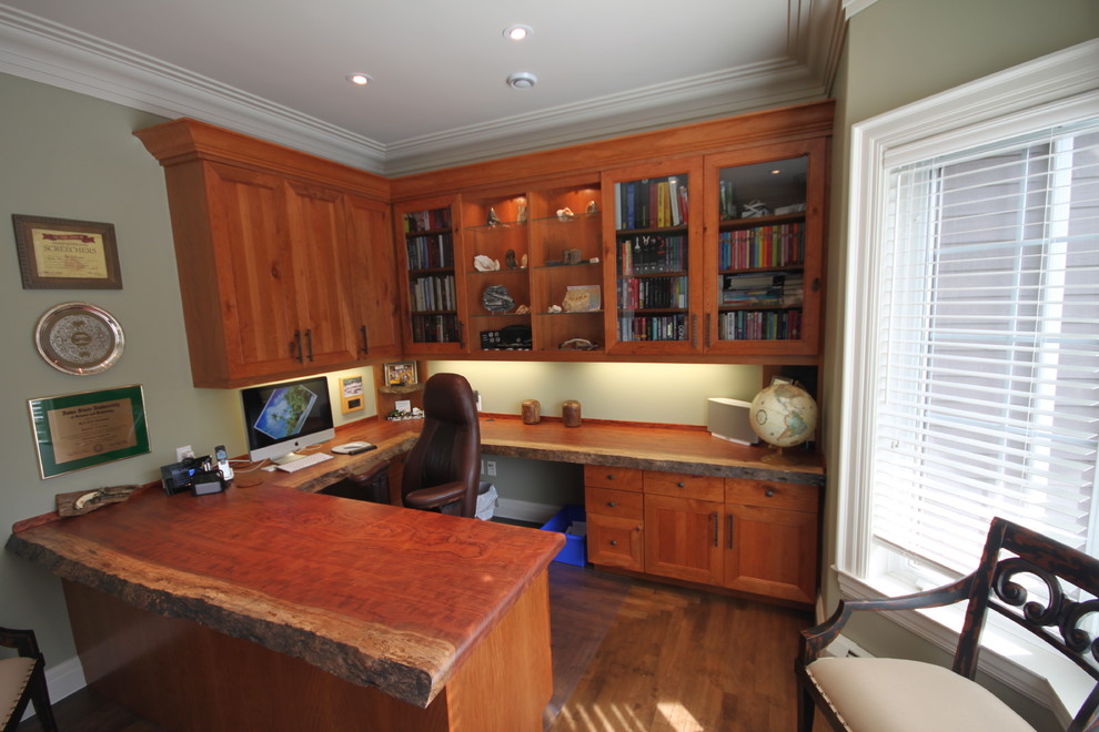 This is an example of a mid-sized country study room in Other with green walls, medium hardwood floors and a built-in desk.